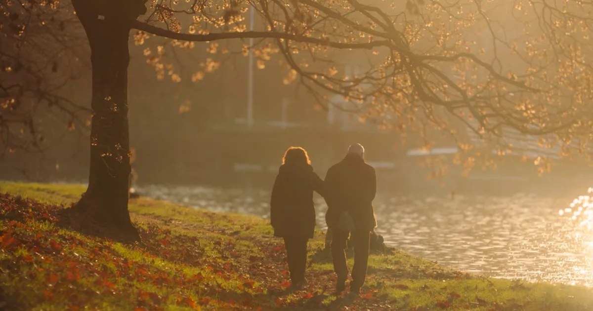 Couple walking by a river at sunset — illustration pour l'article sur L artérite des membres inférieurs, la maladie qu on diagnost