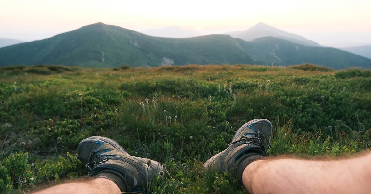 Person sitting on a grassy mountain overlooking hills. — illustration pour l'article sur Marche et circulation sanguine   combien de pas par jour