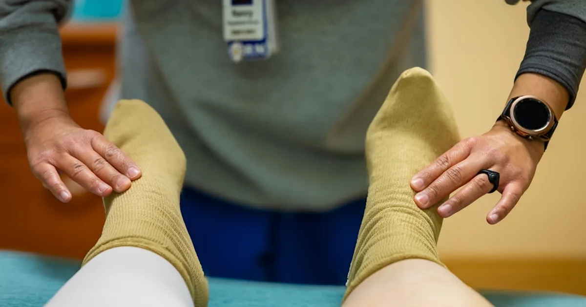 A healthcare worker examines a patient's feet.